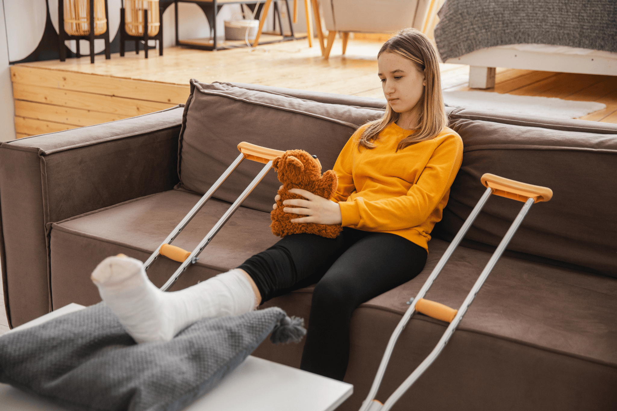 Young girl with broken leg cast sitting on sofa.
